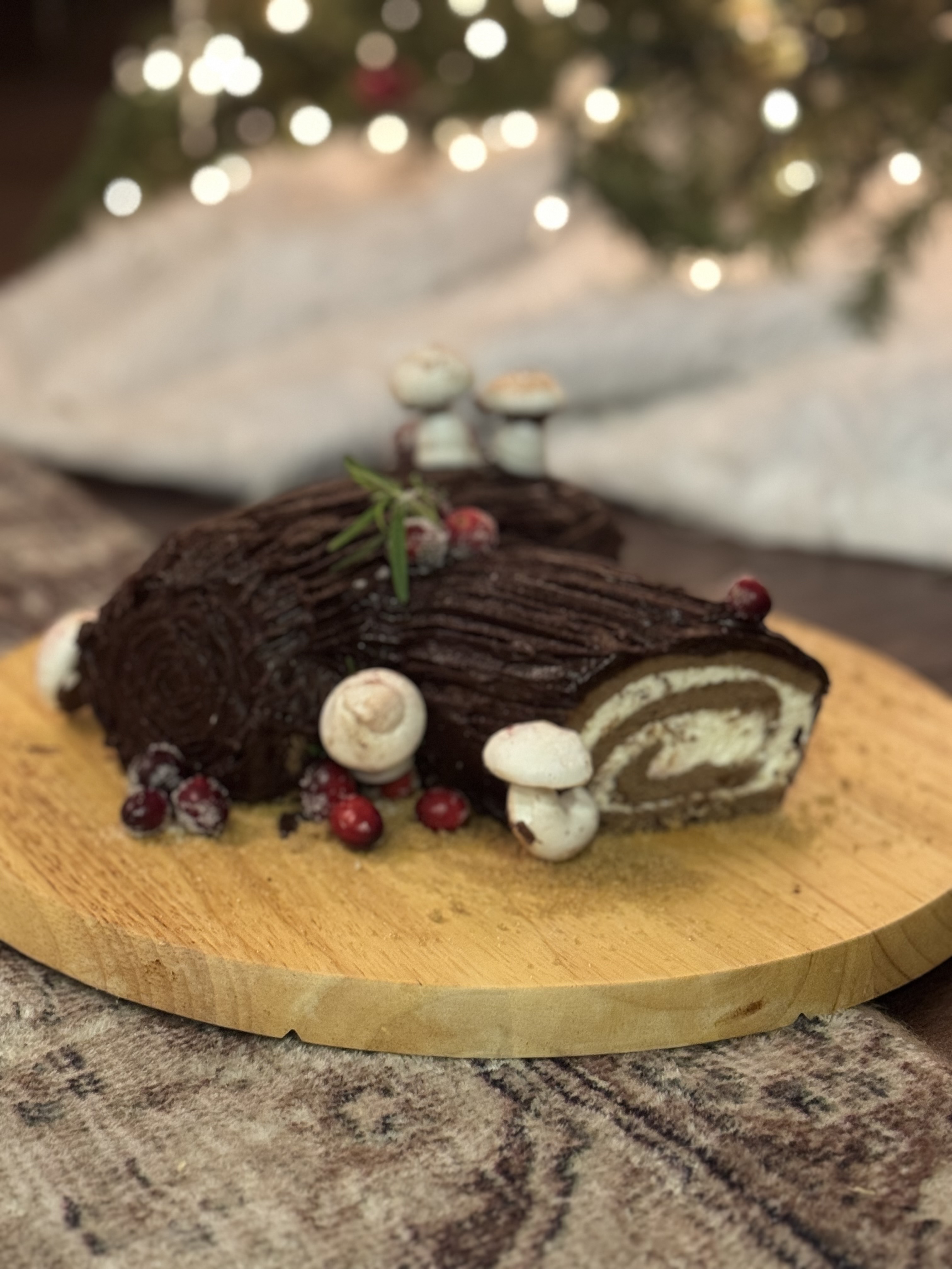 Artisanal chocolate Yule log cake decorated with berries and meringue mushrooms